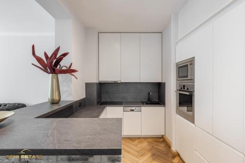 カウナスにあるCentral Kaunas Luxury Apartment with Free Parkingの白いキャビネットと植物の花瓶が備わるキッチン
