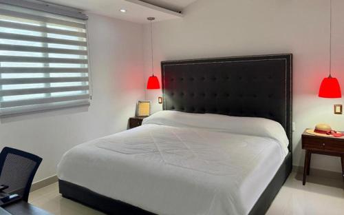 a bedroom with a bed and a desk and red lamps at Residencial Sabina in Cabo San Lucas