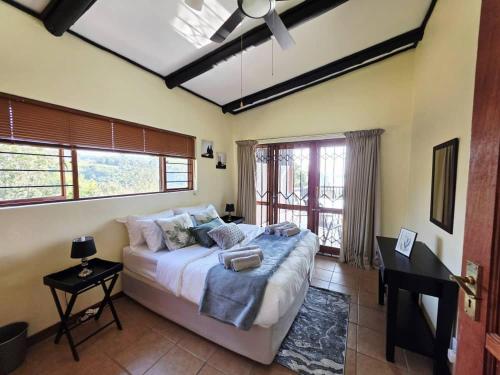 a bedroom with a bed and a desk and windows at Bush Willow Lodge in Hazyview