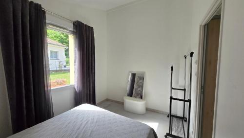 a bedroom with a bed and a window with a toilet at La Maison Greenvallée in Meillonnas