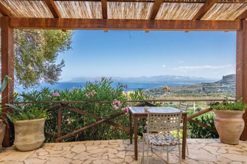 a table and chair on a patio with a view of the ocean at B&B Tre Giummare in Scopello