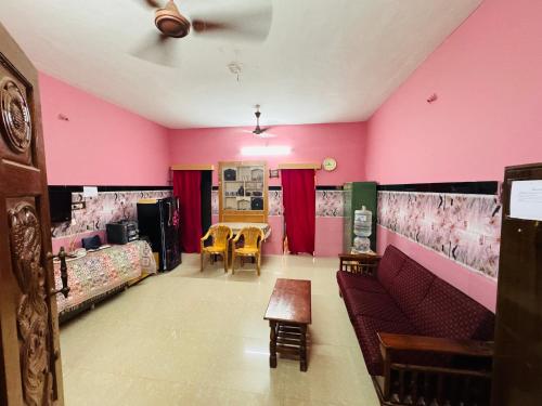 a room with pink walls and a table and chairs at Jose Homestay in Madurai