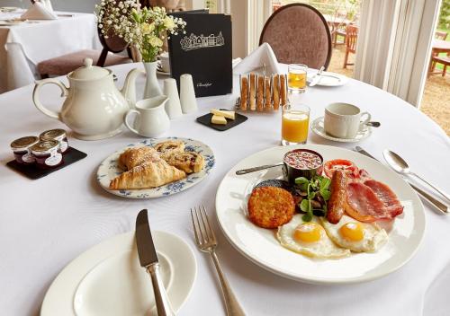 a white table topped with plates of breakfast food at Flitwick Manor Hotel in Flitwick