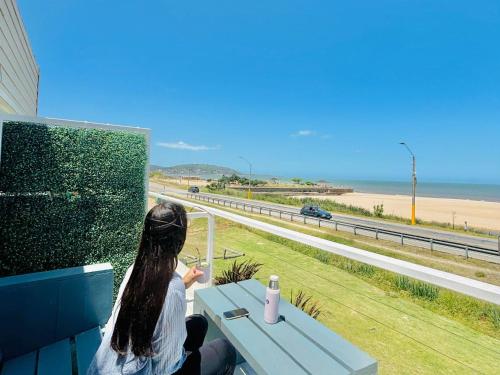 a woman sitting on a bench looking at the ocean at Ramona Boutique Hotel in Piriápolis