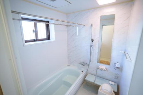 a white bathroom with a tub and a toilet at -The Kabira- The closest private villa to Kabira Bay! Free car rental & BBQ in Ishigaki Island