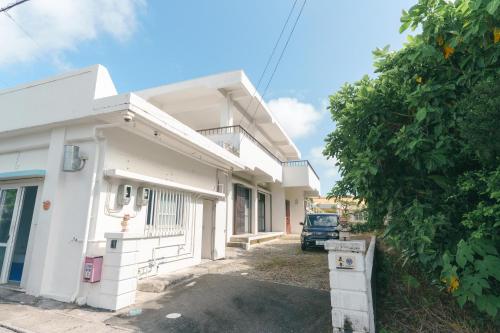 a white house with a car parked in front of it at -The Kabira- The closest private villa to Kabira Bay! Free car rental & BBQ in Ishigaki Island