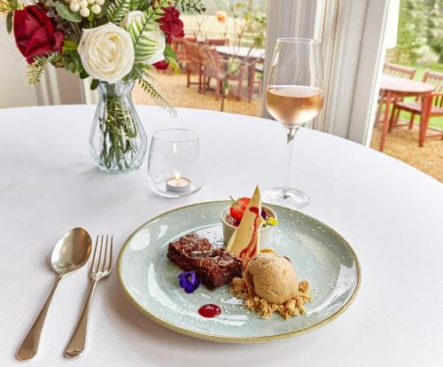 a plate of food on a table with a glass of wine at Flitwick Manor Hotel in Flitwick