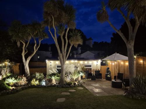 a garden at night with palm trees and lights at Appletorre House Holiday Flats - Pet Friendly by arrangement and Private Parking in Torquay