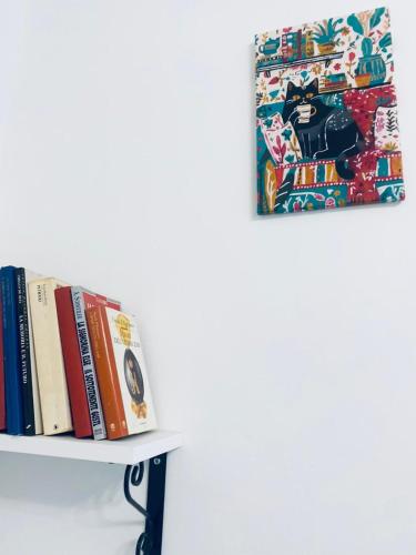 a shelf with books and a painting on a wall at Il mio accogliente giardino all' italiana in San Giovanni Valdarno
