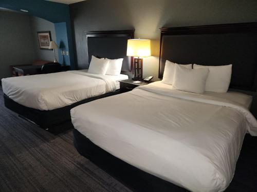 two beds in a hotel room with white sheets at Stay Express Inn & Suites - Mobile, Al in Mobile