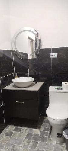 a bathroom with a sink and a toilet and a mirror at Departamento Samir in Manta