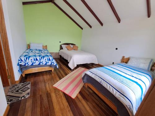 two beds in a room with wooden floors at Palacio del Inca Lodge Isla del Sol in Comunidad Yumani