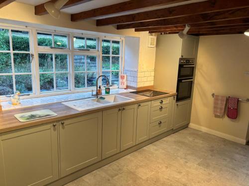 a kitchen with white cabinets and a sink and windows at Willow Cottage in Settrington