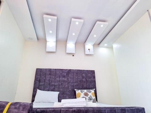 a bedroom with a bed and two lights on the ceiling at Hidden palace Apartments in Mombasa