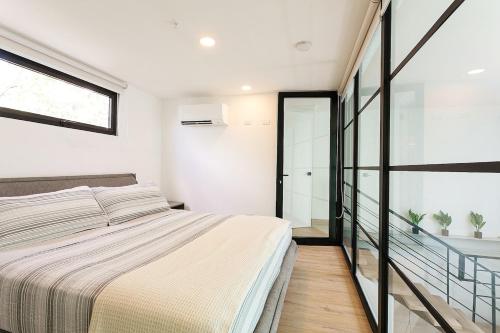 a bedroom with a bed and a glass wall at Casco Viejo 2BR Loft - Rooftop Pool Gym & Balcony in Panama City