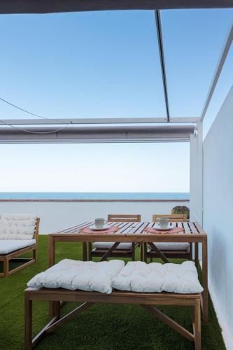 Una mesa y sillas en una habitación con una ventana grande. en Profithome - Vista al Mar Ático Checha, en Candelaria