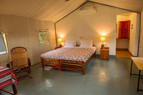 a bedroom with a bed and two chairs in a tent at Birds Murmur glamp in Kuttampuzha