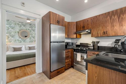 a kitchen with a stainless steel refrigerator next to a bed at Casita Tropical l Walk to DT l Mins to Beach in Saint Augustine