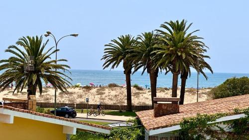 een uitzicht op een strand met palmbomen en een auto bij Villa Santa Bárbara en Isla Canela in Isla Canela