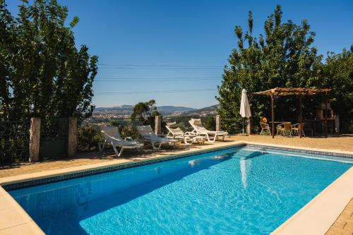 a swimming pool with chairs and a table at Leira da Cruz Grande in Castelo de Paiva
