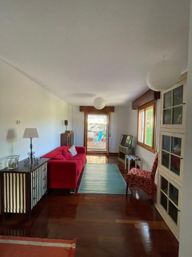 a living room with a red couch and a table at El jardín de Max, apartamento céntrico con jardín privado y parking in Comillas
