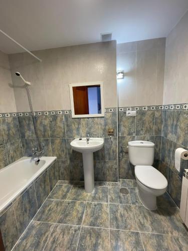 a bathroom with a toilet and a sink and a tub at El jardín de Max, apartamento céntrico con jardín privado y parking in Comillas