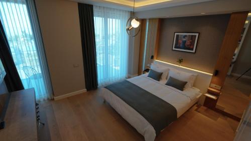 a bedroom with a large bed in a room with windows at RUKA Hotel in Narlıdere