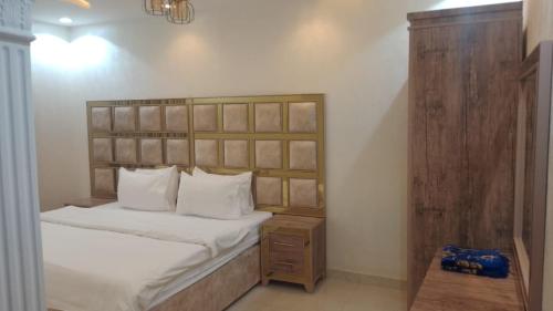 a bedroom with a bed with a wooden headboard at شقق لامير هوم للشقق المخدومة in Khamis Mushayt