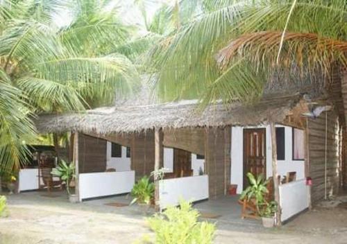 a small building with a straw roof and some palm trees at Skykite Resort & Hostel Kalpitiya Sri Lanka in Kalpitiya