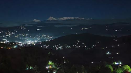 a view of a city at night with mountains at Himalive Homestay in Kausani