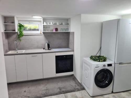 a white kitchen with a washing machine and a refrigerator at Apartmán Zobor in Nitra