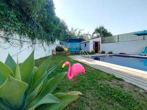 a fake pink flamingo in the grass next to a pool at Vicentina Rooms by Casas do Alentejo in Almograve