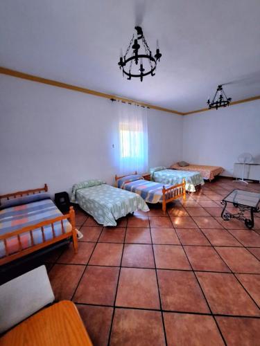 a room with three beds and a chandelier at La Cabaña de la Cigarra in Almodóvar del Río