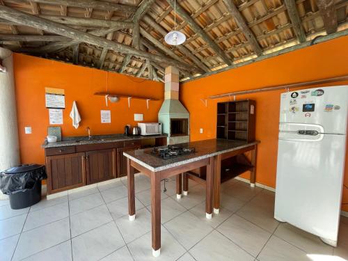 a kitchen with orange walls and a white refrigerator at Pousada Rosamar in Praia do Rosa