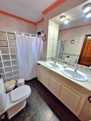 a bathroom with two sinks and a toilet and a mirror at La Cabaña de la Cigarra in Almodóvar del Río