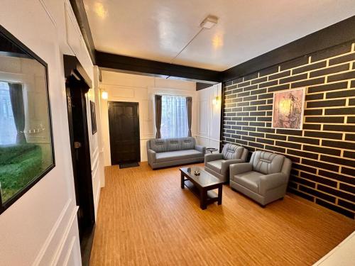 a living room with two couches and a brick wall at Roy-al Homestay 1 in Shillong