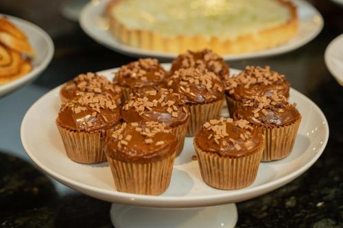 a plate of cupcakes with chocolate frosting and a pie at Hotel Querência in Gramado