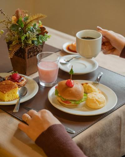 a table with plates of breakfast foods and a cup of coffee at Hotel Querência in Gramado