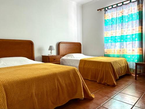 a bedroom with two beds and a window with curtains at Casa do Cisne in Porto Santo