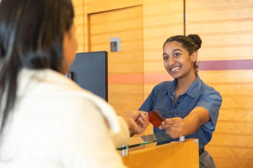 a woman is handing a woman a credit card at ibis Contagem Ceasa in Contagem