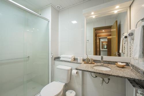 a bathroom with a toilet and a sink and a mirror at Hotel Querência in Gramado