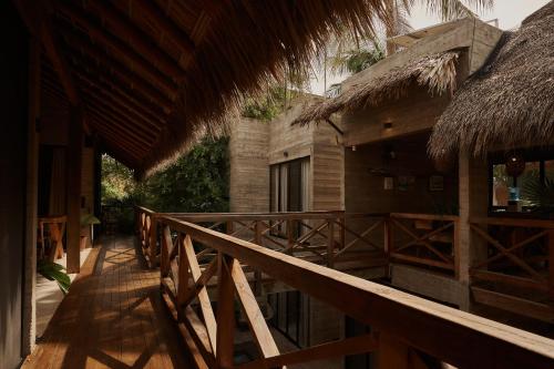 a wooden walkway next to a building with a thatch roof at Punta Tamarindo in Puerto Escondido