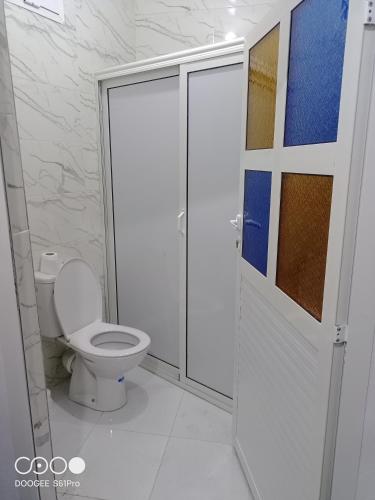 a bathroom with a toilet and a glass shower door at Ait Mouli Agdal Retreat in Douar Debra