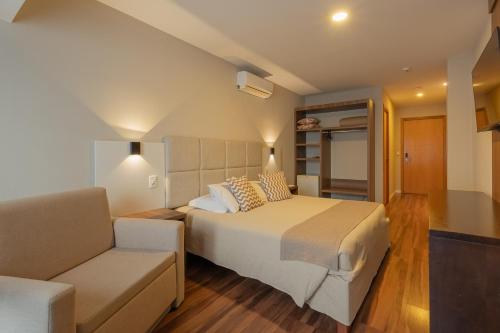 a bedroom with a large bed and a couch at Hotel Querência in Gramado