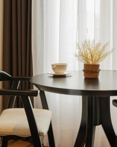 a table with a cup of coffee and a plant on it at Hotel Querência in Gramado