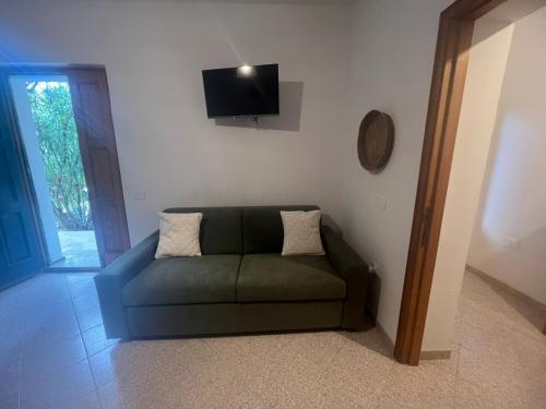 ein grünes Sofa im Wohnzimmer mit einem TV in der Unterkunft Appartamento fronte spiaggia in Bari Sardo