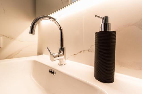 a black soap dispenser sitting on top of a sink at Beach And Mountain Apartment in Sesimbra