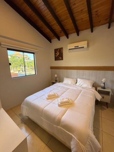 a bedroom with a large white bed with two towels on it at Departamentos DE LA COSTA in Encarnación
