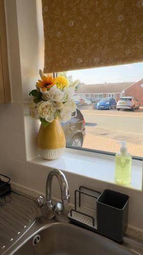 un jarrón de flores sentado en un alféizar junto a un fregadero en Peaceful Springfield Studio, en Chelmsford