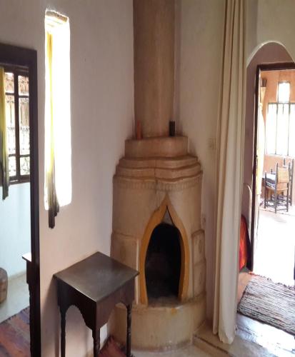 a fireplace in a room with a table next to it at Riad Cascades d'Ouzoud in Ouzoud